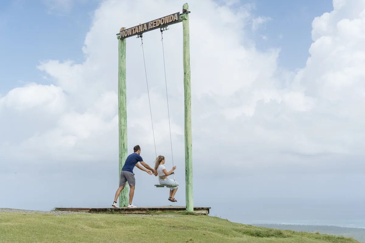 Couple at the named Montaña Redonda swing with the Atlantic coast in the distance