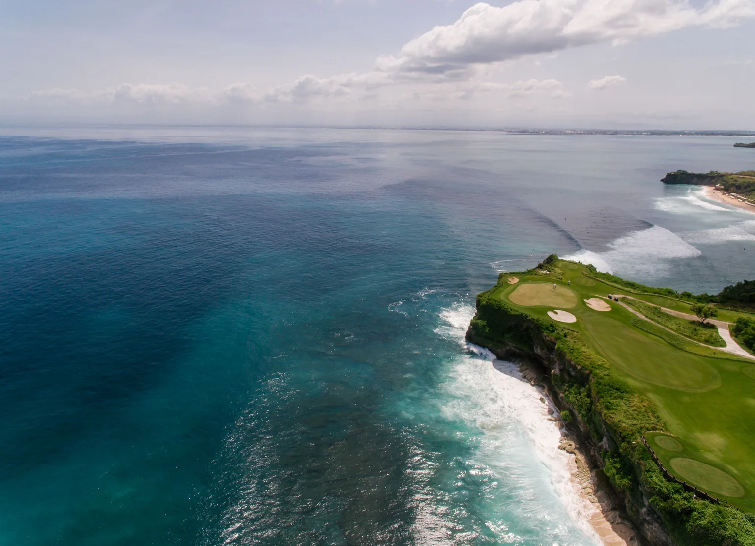 Aerial view of a coastal golf course beside turquoise water