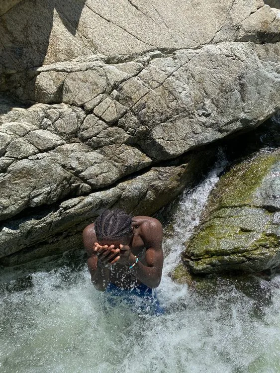 Person standing beneath a waterfall in the Dominican Republic