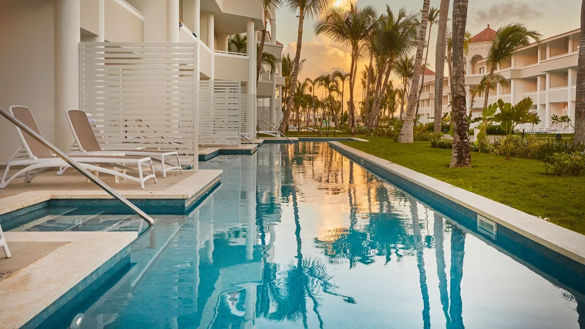 Swim-up pool and room terraces at Bahia Principe Escape Ambar at sunset