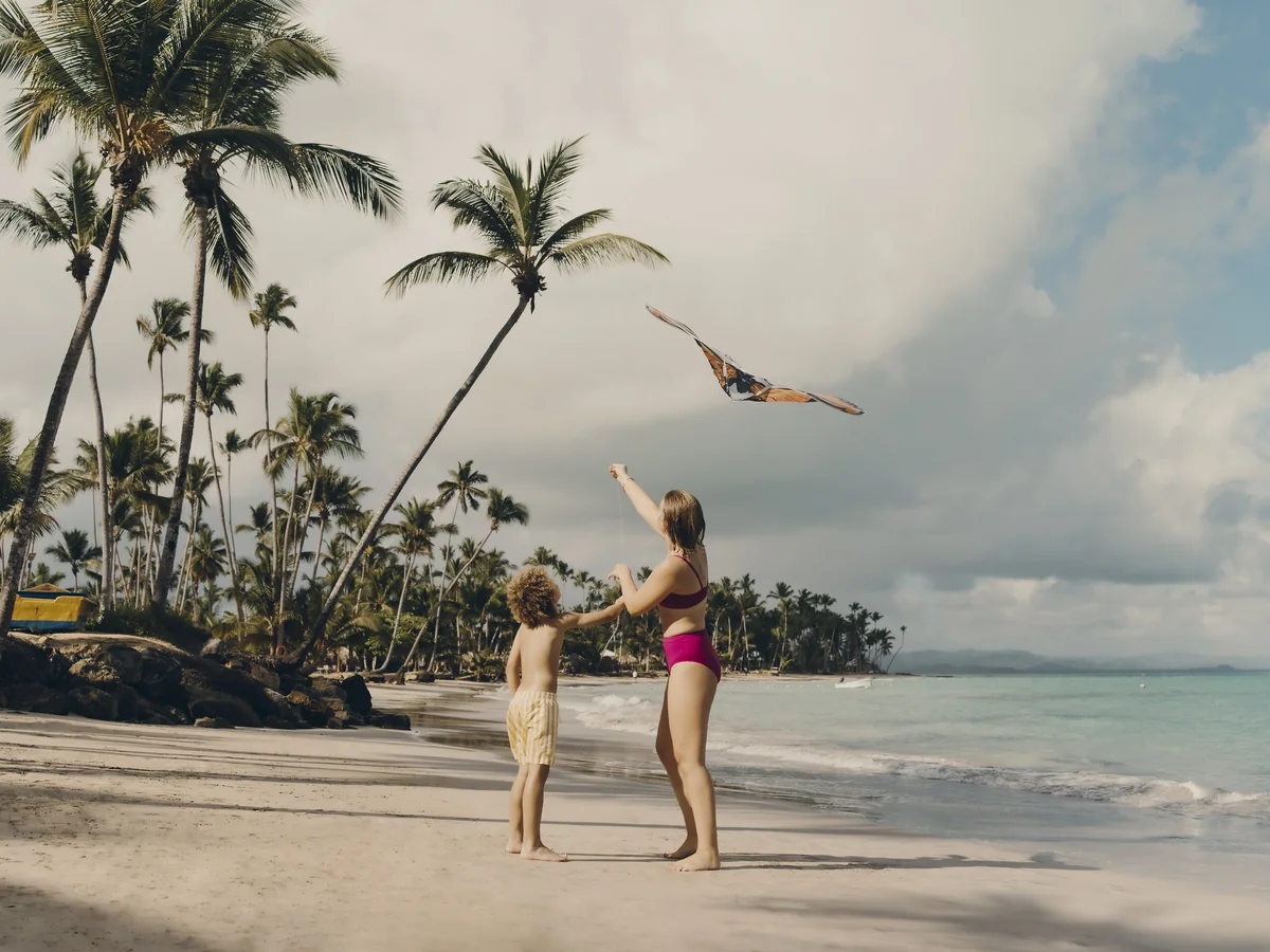 An adult and child flying a kite on the Club Med Michès beach