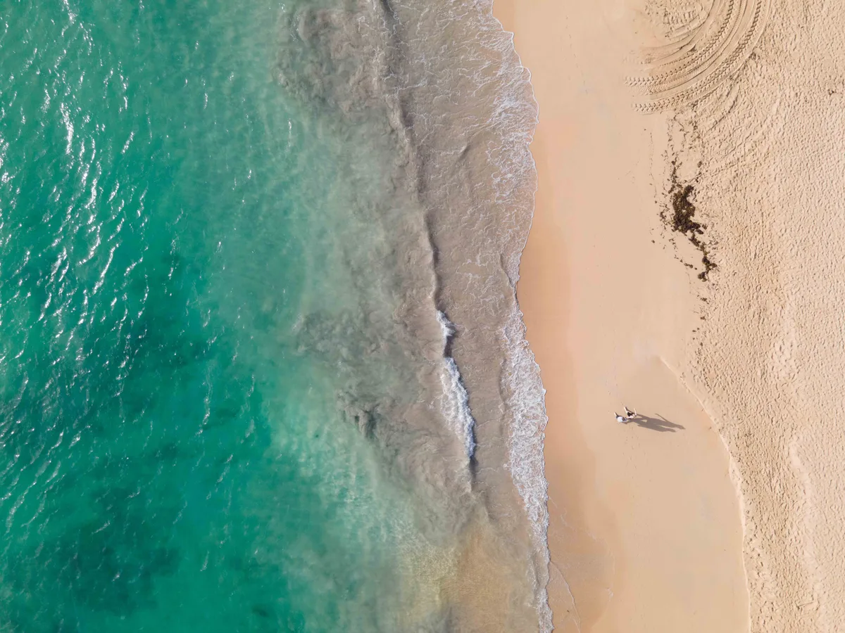Aerial view of two people walking along a turquoise Dominican Republic shoreline