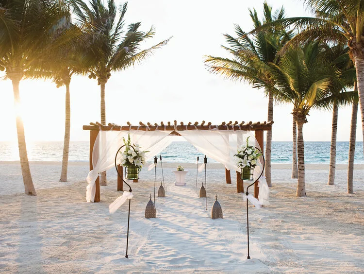 Beachside wedding pergola with white drapery and palms on the sand at Excellence Carmen Punta Cana