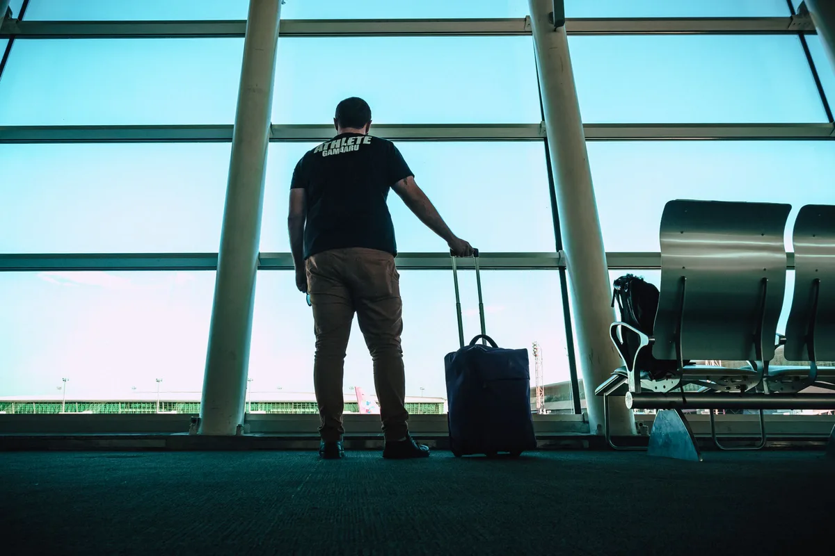 Traveller with luggage in a generic airport lounge for arrival-planning context